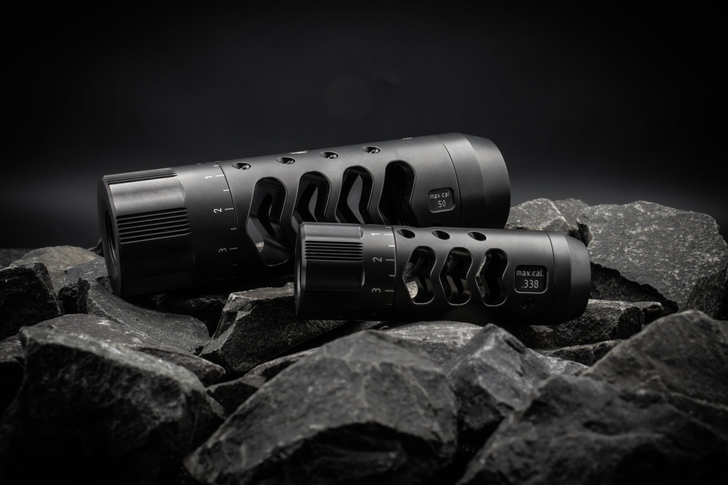 Sinus Brake Tuner Mündungsbremse für PRS und Long Range – Präzisionsdesign aus rostfreiem Edelstahl mit DLC+ Beschichtung, Made in Germany. Große Magnum Brake und normale Sinus Brake liegen auf einem Stein. 